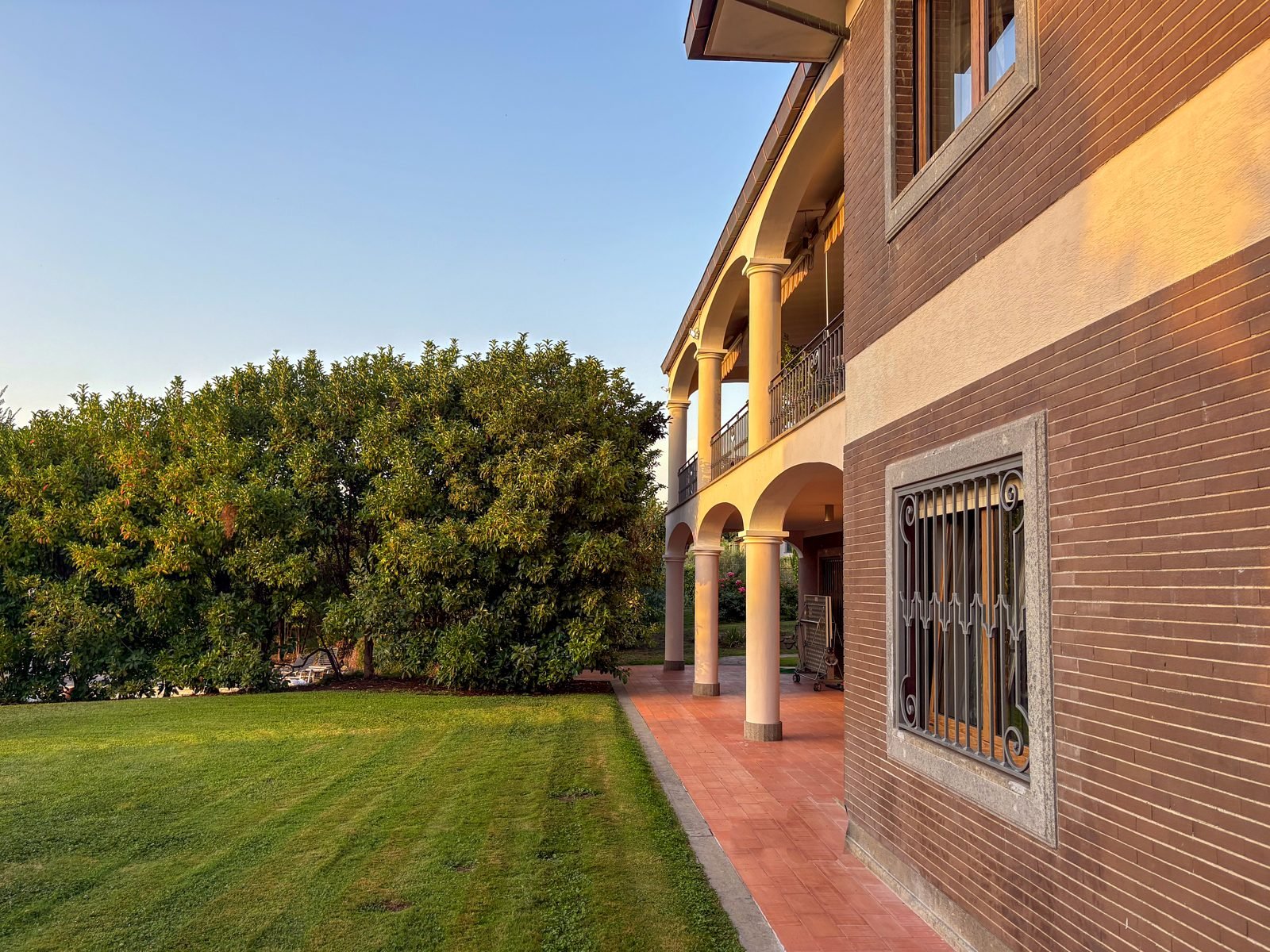The house at golden hour: arches, loggia and lawn