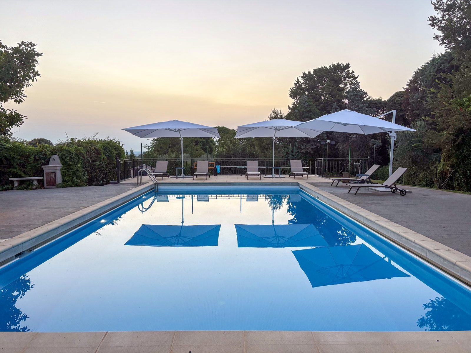 The pool at sunset with white umbrellas and loungers