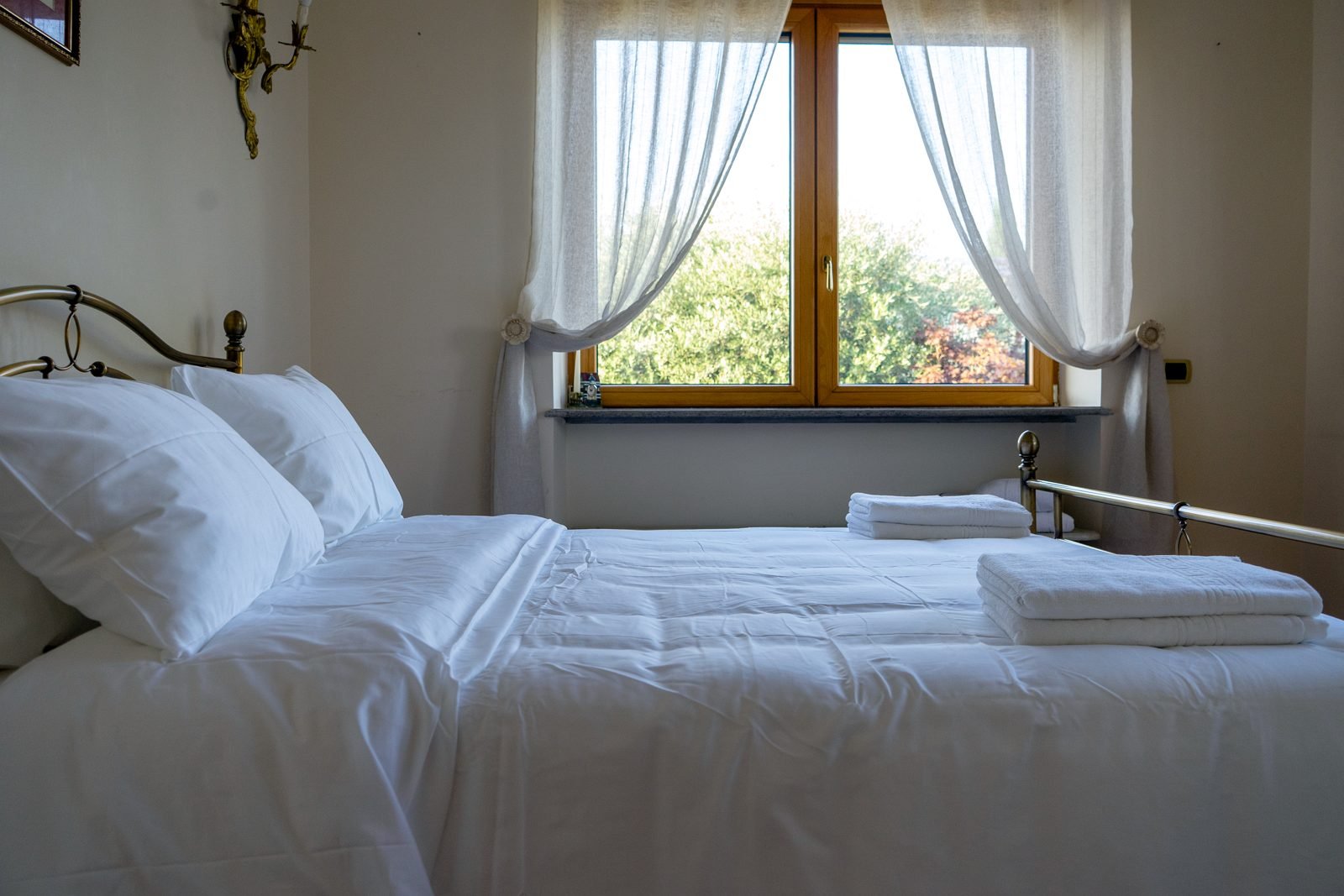 A bedroom with brass bed and garden view